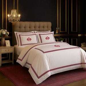 Puede incluir: Juego de cama blanco con monograma y ribete burdeos. El juego incluye una funda n&oacute;rdica y dos fundas de almohada, cada una con un monograma de tres letras. La cama est&aacute; hecha con una alfombra burdeos y un cabecero de tonos neutros.