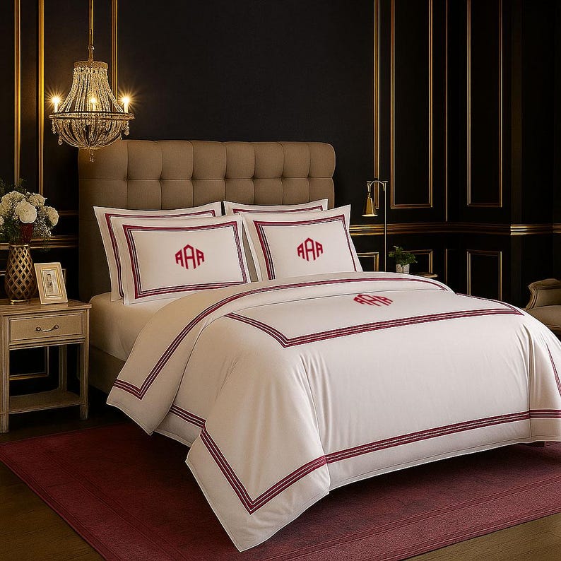 Puede incluir: Juego de cama blanco con monograma y ribete burdeos. El juego incluye una funda n&oacute;rdica y dos fundas de almohada, cada una con un monograma de tres letras. La cama est&aacute; hecha con una alfombra burdeos y un cabecero de tonos neutros.