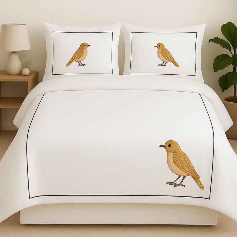 Puede incluir: Un juego de cama blanco que consta de una funda n&oacute;rdica y dos fundas de almohada, cada una con un borde rectangular negro fino y una ilustraci&oacute;n de un peque&ntilde;o p&aacute;jaro marr&oacute;n mirando hacia la izquierda, impresa sobre la tela.