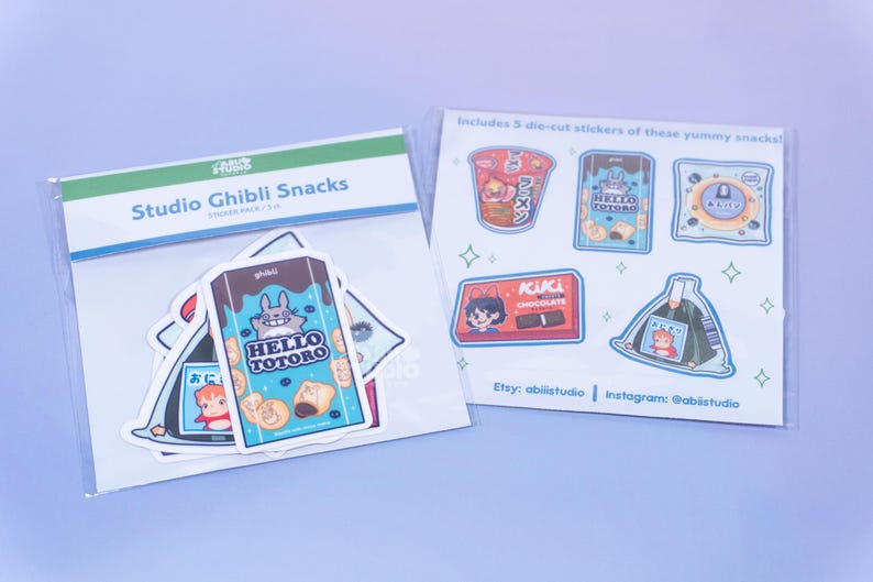May include: Two packs of Studio Ghibli Snacks stickers. One pack features the text "Studio Ghibli Snacks" and includes stickers with the text "HELLO TOTORO". The other pack includes five die-cut stickers of snacks, with the text "ACUACL CHOCOLATE" and "ラーメン".