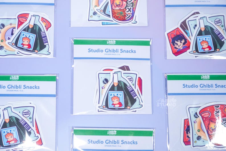 May include: Multiple packs of Studio Ghibli Snacks stickers. Each pack contains several stickers with colorful illustrations of anime food and characters. The stickers are packaged in clear plastic with a green and white header that reads "Studio Ghibli Snacks".