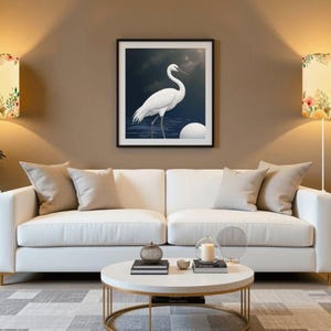 May include: A living room scene featuring a white sofa, a round coffee table, and a framed artwork of a white bird. Two wall sconces with floral patterned shades flank the artwork. The room has a neutral color palette with a patterned rug.