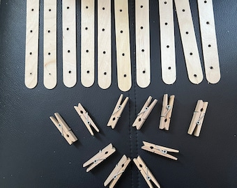 May include: A set of wooden craft sticks with holes and a set of wooden clothespins. The sticks are arranged in rows and the clothespins are arranged in a circle.