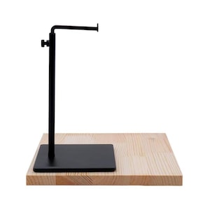 May include: A black metal display stand with a horizontal arm, mounted on a rectangular wooden base. The stand is designed to hold an item, with a simple, minimalist aesthetic. The wooden base has a natural wood grain.