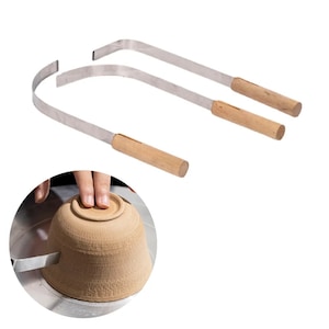 Op de afbeelding: Twee metalen pottenbakkerstools met houten handvatten. De gereedschappen zijn gebogen en hebben een scherpe rand. De gereedschappen worden gebruikt om de randen van potten te trimmen.