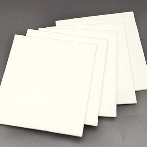 May include: A stack of six white felt squares, likely for crafting or other creative projects.