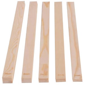May include: Five unfinished wooden strips of varying thicknesses, ranging from 3mm to 7mm. Each strip is a light, natural wood color with visible grain patterns. The measurements are printed on the end of each strip.