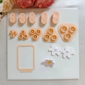 Op de afbeelding: Een set siliconen mallen voor het maken van sieraden. De mallen zijn in verschillende vormen, waaronder cirkels, bloemen en een rechthoek met de tekst "1.5MM".