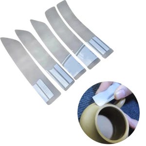 Può includere: Cinque strisce di plastica trasparente con retro adesivo per proteggere le superfici dai graffi. Le strisce sono curve e hanno un'etichetta bianca con testo nero. Una mano è mostrata mentre applica una delle strisce a una tazza di ceramica.