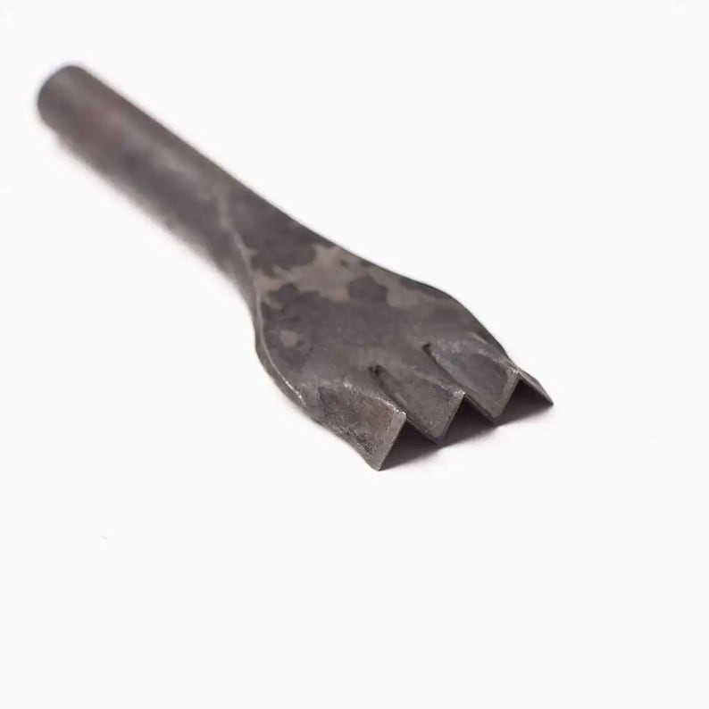 May include: A metal tool with a long handle and a three-pronged head. The tool is used for punching holes in leather.