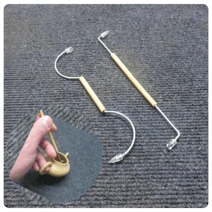 Peut inclure: Deux outils argentés avec des manches en bois et des pointes en plastique transparent. Les outils ont un design incurvé et sont placés sur une surface grise. Un petit objet en céramique beige est tenu dans une main en bas à gauche.