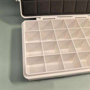 Op de afbeelding: Witte plastic opbergdoos met een scharnierend deksel en meerdere vakken. De doos is leeg en klaar om gevuld te worden.