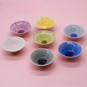 Könnte beinhalten: Eine Sammlung von sieben kleinen Keramikschalen mit einer Craquelé-Glasur. Die Schalen sind in einer Gruppe angeordnet und weisen eine Vielzahl von Farben auf, darunter Violett, Gelb, Hellblau, Weiß, Hellgrün, Dunkelblau und Dunkelgrau.