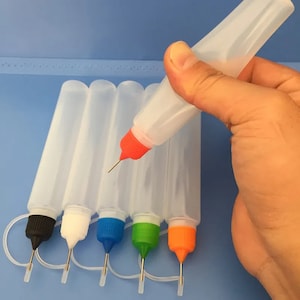 Pode incluir: Seis garrafas de plástico transparentes com conta-gotas coloridos. As garrafas são projetadas para encher e dispensar líquidos. As garrafas têm uma ponta de agulha longa e fina para uma aplicação precisa.