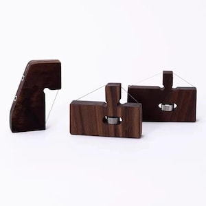 May include: Three dark brown wooden clay cutters with thin metal wires. Each tool features a rectangular or angled block design with a central silver-coloured metal adjustment knob and a taut wire stretched across the top for slicing through clay.