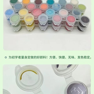 K&ouml;nnte beinhalten: Eine Sammlung kleiner Farbt&ouml;pfe in verschiedenen Farben, darunter Blau, Rosa, Gelb und Gr&uuml;n. Die Farbt&ouml;pfe sind in Reihen angeordnet und gebrauchsfertig. Das Bild enth&auml;lt auch Text auf Chinesisch.