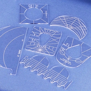 Puede incluir: Un conjunto de siete plantillas de acolchado de plástico transparente para crear diferentes formas y diseños. Las plantillas incluyen una espiral de 15 cm, un arco de 10 cm, un círculo con un diámetro de 14 cm, una plantilla sin alfileres n.º 4, un copo de nieve de 18 cm y dos plantillas con bordes ondulados.