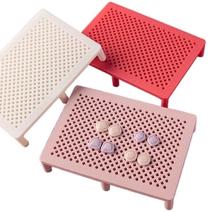 May include: Three colorful pegboards in white, red, and pink, each with a grid of small holes. The pink board has several small, round, and square pegs in various pastel colors. The pegboards have short legs.