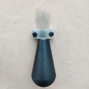 May include: A black handled tool with a silver metal head and multiple thin metal prongs. The tool is used for scoring leather.
