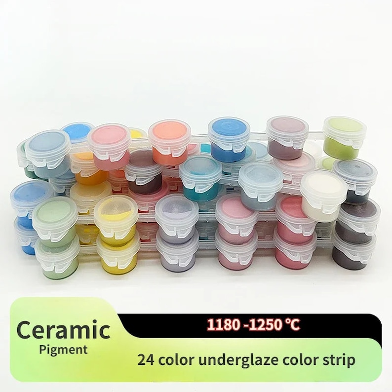 K&ouml;nnte beinhalten: Eine Sammlung von 24 Keramikpigmentfarben in kleinen, transparenten Kunststoffbeh&auml;ltern mit wei&szlig;en Deckeln. Die Beh&auml;lter sind auf transparenten Kunststoffschalen gestapelt. Der Text "Ceramic Pigment" und "24 color underglaze color strip" ist sichtbar.