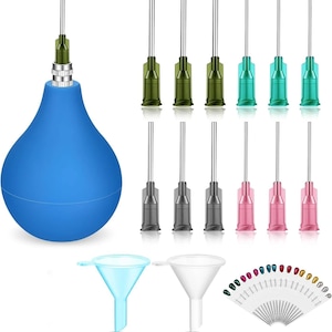 Puede incluir: Una jeringa de bulbo azul con punta de metal, junto con varias puntas de aguja de colores y embudos. Las puntas de las agujas son verdes, grises y rosas. Los embudos son azules y blancos. Una variedad de puntas de aguja están abanicadas.