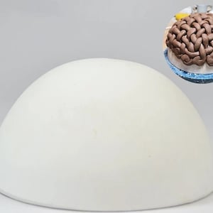 May include: White ceramic cake dome for baking and decorating cakes. The dome is smooth and round with a white finish.