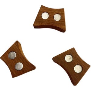 May include: Three wooden magnetic holders with a curved design. Each holder is a warm brown color and features two silver-colored circular magnets. The holders are arranged against a white background.