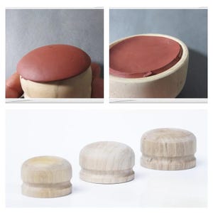 Puede incluir: Colección de tapones de botella de madera. Los tapones son cilíndricos con una parte superior redondeada. La madera tiene un color claro natural. Una imagen muestra un tapón con una sustancia marrón rojiza dentro de un recipiente de madera.