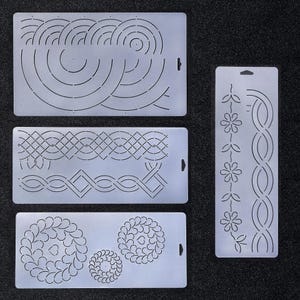 May include: Four white plastic quilting stencils with different designs. The stencils are for free motion quilting and feature a variety of geometric and floral patterns.