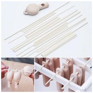 Può includere: Una collezione di tasselli in legno beige chiaro e un oggetto in ceramica beige con un foro. L'immagine mostra anche un primo piano dei tasselli utilizzati per tenere piccoli oggetti in ceramica beige su un supporto bianco. Gli oggetti sembrano essere teste di bambola.
