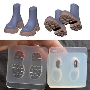 以下が含まれることがあります： 茶色のソールが付いた青いアンクルブーツと、それらを作るためのシリコンモールド。ブーツは分厚いソールデザインです。透明なモールドはブーツのソールの形状を示しています。