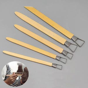 May include: Five wooden sculpting tools with metal tips. The tools are different sizes and have a loop at the end of the metal tip.