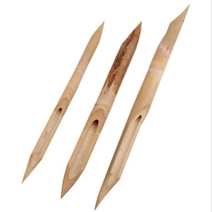 May include: Three light brown bamboo calligraphy pens of varying thicknesses, each featuring a pointed tip and a carved ink reservoir channel along the shaft. The natural wood grain and nodes are visible on the surface of each tool.