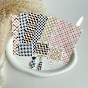 Könnte beinhalten: Ein Set aus drei Keramikbechern mit gesprenkelter, matter Oberfläche. Die Becher sind in Creme-, Hellgrau- und Dunkelgrautönen gehalten. Jeder Becher hat ein schlichtes, minimalistisches Design.