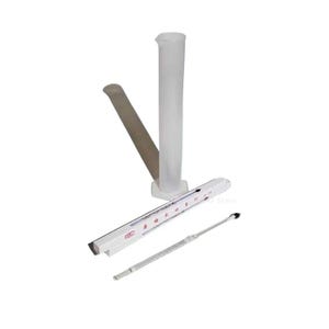 May include: A clear plastic graduated cylinder, a thermometer, and a metal tool are arranged on a white surface. The cylinder is tall and cylindrical with measurement markings. The thermometer is in a white case. The metal tool has a small, pointed end.