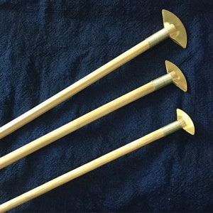 May include: Three wooden dowels with brass tips. The tips are shaped like a crescent moon and are attached to the dowels with a metal screw.
