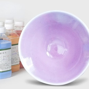 Peut inclure: Un bol en céramique blanche avec un glaçage violet clair. Le bol est vide et a une finition lisse et brillante.
