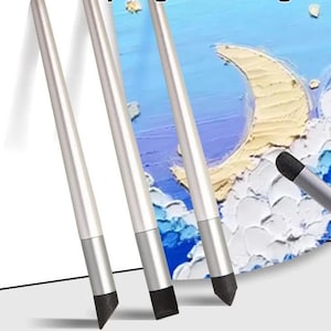 Può includere: Quattro strumenti artistici con manici cilindrici color argento e punte in spugna grigio scuro, sode e appuntite. Questi strumenti sono posizionati in diagonale su un dipinto materico che raffigura una luna crescente gialla su un cielo blu e bianco.