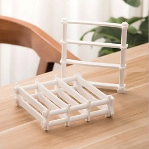 May include: White plastic expandable shelf dividers for organising kitchen cabinets or drawers. The dividers are adjustable and can be used to create custom compartments.