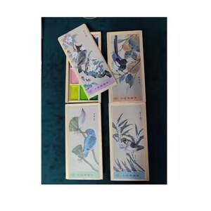 May include: Watercolor paint set with bird illustrations. The set includes a wooden box with watercolor pans and several rectangular boxes with bird and floral designs. The bird illustrations are in shades of blue, green, and gray.