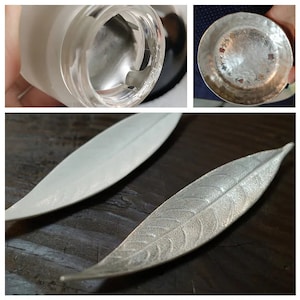 May include: Two silver leaf-shaped incense holders. One holder is smooth and the other has a textured leaf design.