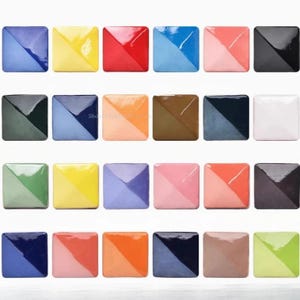 Puede incluir: Una cuadrícula de veinticuatro baldosas cerámicas cuadradas, cada una con una combinación de colores de dos tonos única. Los colores incluyen azul, amarillo, rojo, rosa, negro, verde, naranja y marrón. Las baldosas están dispuestas en una matriz de cuatro por seis.