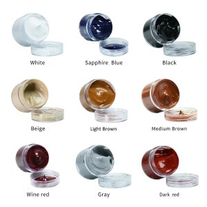 May include: Ten small jars of leather dye in various colours, including white, beige, light brown, medium brown, sapphire blue, black, wine red, grey, and dark red. Each jar has a clear lid.