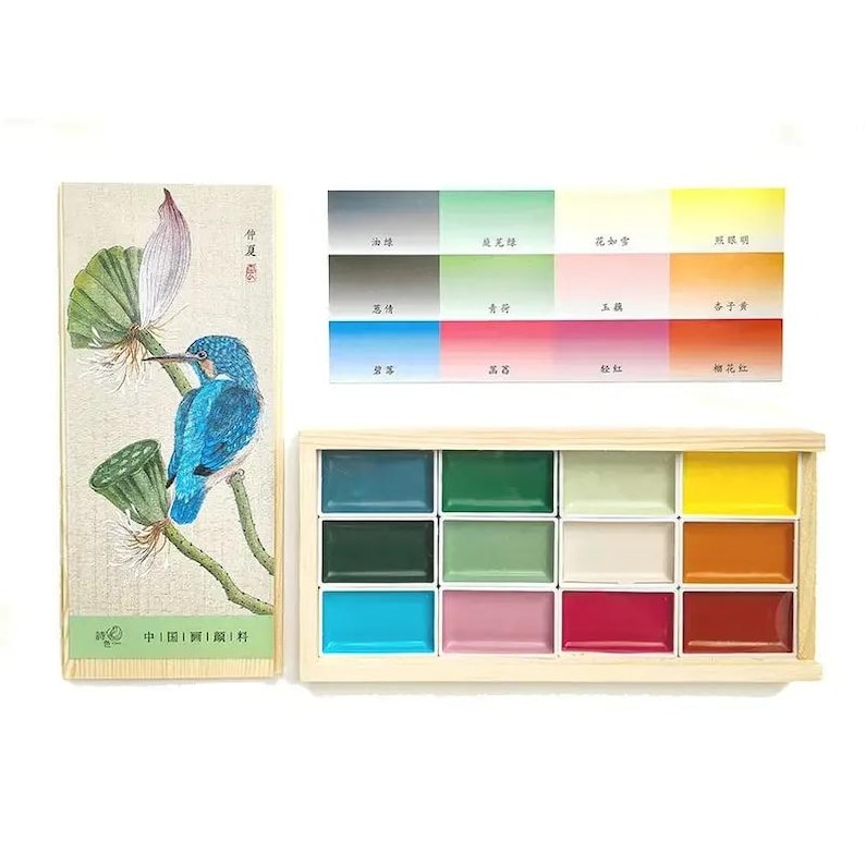 May include: A watercolor paint set with a wooden box containing 12 vibrant colors. The set includes a color palette and a box with a painting of a blue bird on a branch with a lotus flower.