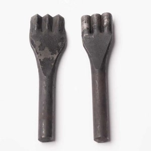 May include: Two metal leather punches with different sized prongs. The punches are black and have a worn, aged look.