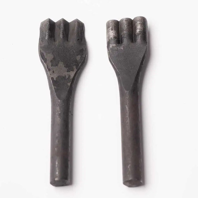 May include: Two metal leather punches with different sized prongs. The punches are black and have a worn, aged look.