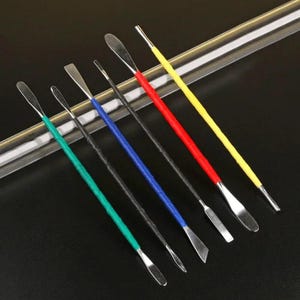 Può includere: Un set di sei strumenti in acciaio inossidabile con manici colorati. I manici sono avvolti in verde, nero, blu, rosso e giallo. Gli strumenti hanno punte di forme diverse.