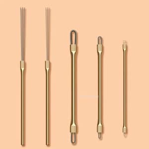 Puede incluir: Una colección de cinco herramientas doradas, cada una con un diseño único. Dos herramientas tienen múltiples extremos finos en forma de alambre, mientras que otras presentan puntas en bucle o planas. Las herramientas están dispuestas verticalmente sobre un fondo color melocotón.
