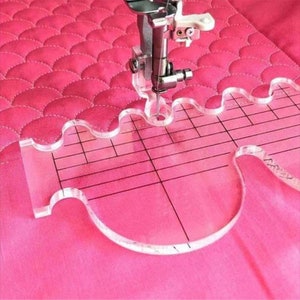 Peut inclure: Une r&egrave;gle de quilting en plastique transparent avec un bord ondul&eacute; et une grille. La r&egrave;gle est utilis&eacute;e pour guider l'aiguille d'une machine &agrave; coudre.