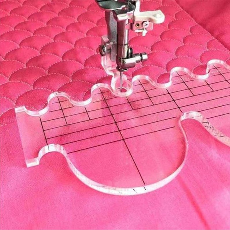 Peut inclure: Une r&egrave;gle de quilting en plastique transparent avec un bord ondul&eacute; et une grille. La r&egrave;gle est utilis&eacute;e pour guider l'aiguille d'une machine &agrave; coudre.